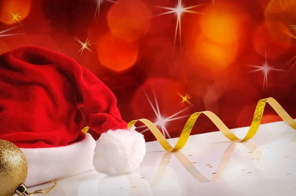 Cappello Babbo Natale con palla d'oro e nastro rosso sfondo — Foto Stock