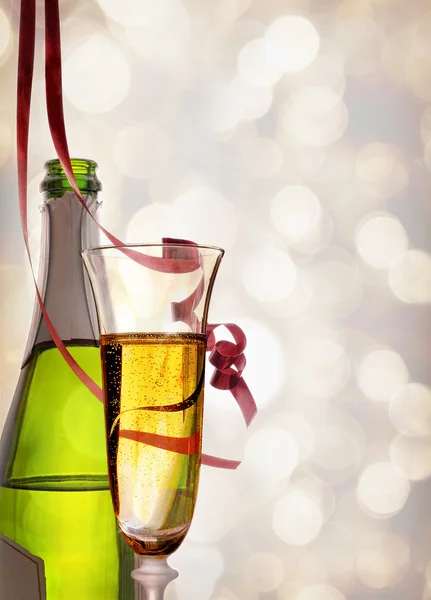 Glass and bottle of sparkling white wine and ribbons hanging — Stock Photo, Image