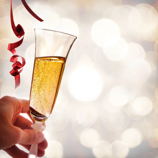 Hand holding a glass of sparkling white wine and ribbons — Stock Photo, Image