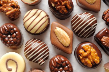 Assorted aligned bonbons on a white textured paper Top view