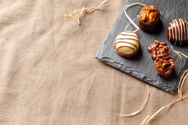 Assorted bonbons on a slate plate with straw decoration top — Stockfoto