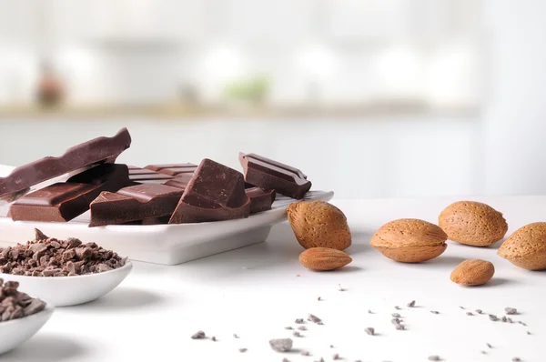 Portions et pépites de chocolat sur des récipients aux amandes en cuisine — Photo