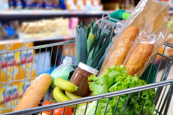 Carrito de compras lleno de comida en la vista lateral del supermercado — Foto de Stock