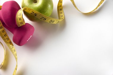 Pink dumbbells with apple and tape measure diagonal top 