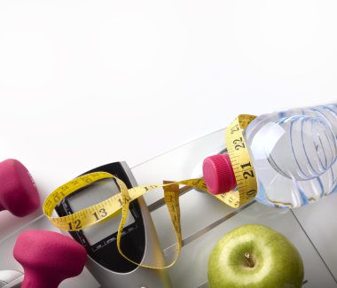 Scale with dumbbells bottle apple and tape measure top