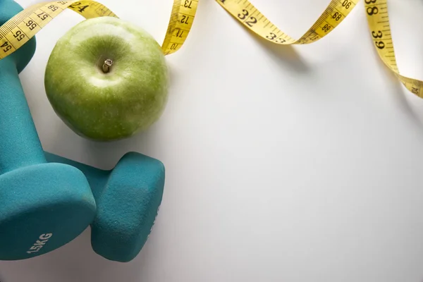 Dumbbells with apple and tape measure top — Stockfoto