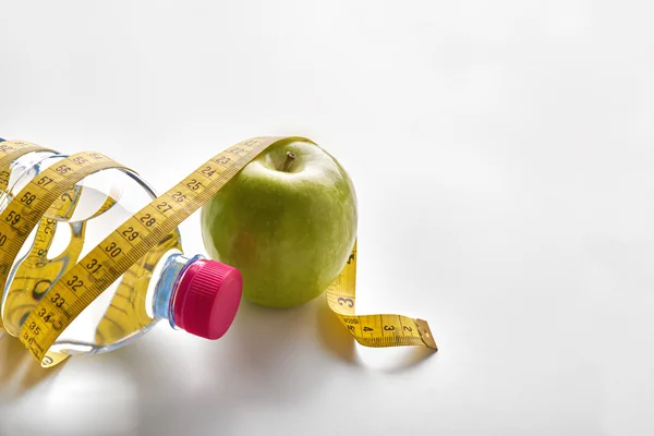 Measuring tape around a bottle of mineral water and apple — Stok fotoğraf