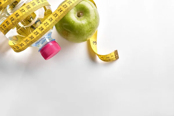 Measuring tape around a bottle of water and apple top — Stok fotoğraf