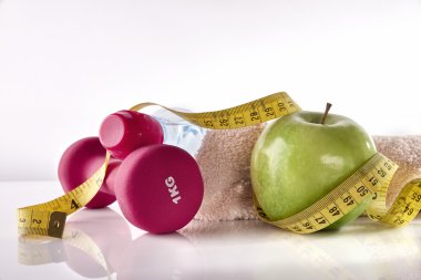 Apple dumbbells and tape measure on white table front isolated