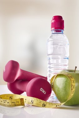 Apple dumbbells and tape on gym white table front view