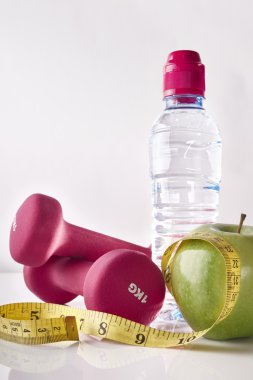 Apple dumbbells tape and bottle on white table front isolated