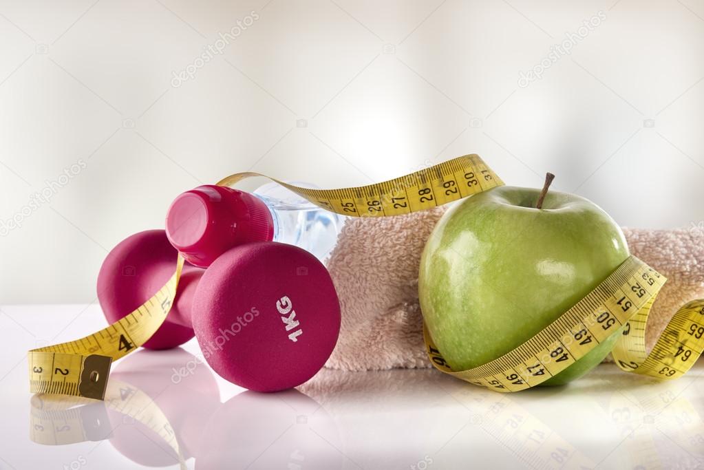 Apple dumbbells and tape measure on white table front gym
