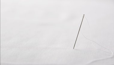 İş parçacığı üzerinde beyaz bez önden görünüm ile iğne