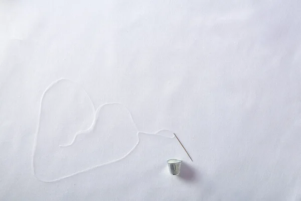 Threading needle thread forming a heart  background top view — Stock Photo, Image