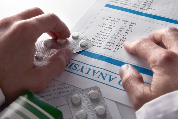 Médecin prescrivant des médicaments et montrant un rapport de test sanguin élevé — Photo