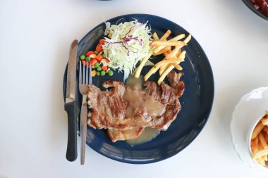 Kızarmış patates ve sebzeli domuz bifteği.