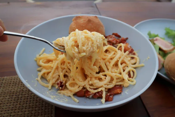 ladling spaghetti , pasta or spaghetti carbonara and bread