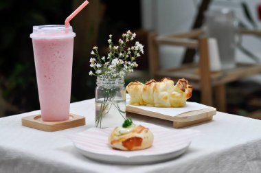Çörek, ekmek ya da badem ekmeği ya da tereyağlı ekmek ve çilekli smoothie.