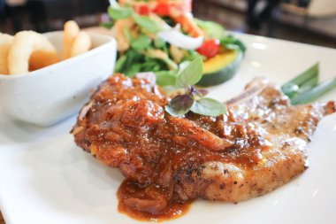 Izgara domuz eti, domuz eti ya da domuz pirzolası ve soğan halkası ve servis için salata.