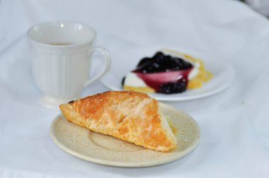 Ananas soslu börek, turta ve masada cheesecake ile servis edilen sıcak çay.