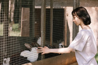 A girl feeds rabbits on a farm