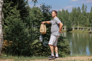 Nehrin kenarındaki ormanda neşeyle dans eden bir adam.