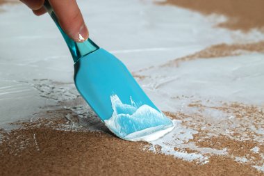 Bir adam beyaz alçıyı bir spatulayla sürer..