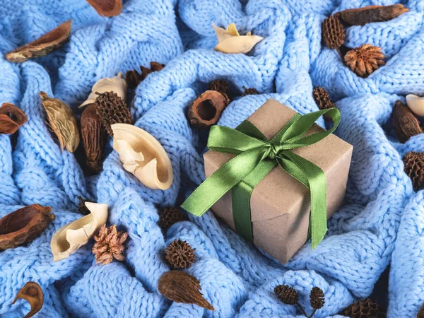 Un regalo en papel artesanal y cinta verde sobre el fondo de punto de lana. —  Fotos de Stock