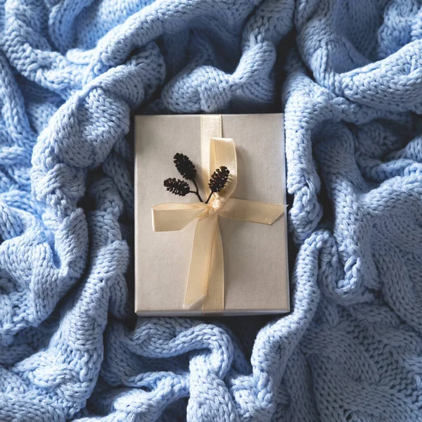 El paquete blanco para regalos en el fondo de punto de lana azul pálido. —  Fotos de Stock