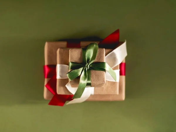 Hermoso lleno de tres regalos con cintas de satén y papel artesanal sobre el fondo verde. —  Fotos de Stock