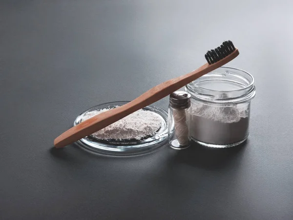 Zero waste concept for teeth cleaning. The bamboo toothbrush with the floss and toothpowder in the glass on the grey background. — Stock Photo, Image