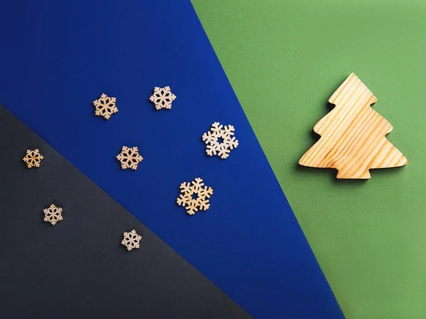 The zero waste new year concept as a wooden fir tree and falling wooden snowflakes on the multicolor background. — Stock Photo, Image