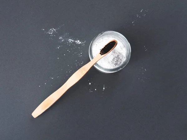 A bamboo toothbrush with toothpowder in a glass on the grey background. — Stock Photo, Image
