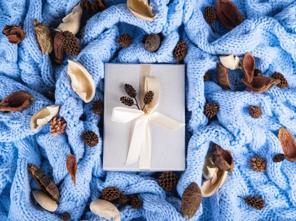 El paquete blanco para regalos en el fondo de punto de lana azul pálido. — Foto de Stock