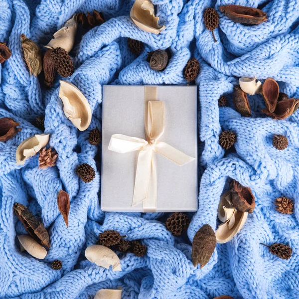 El paquete blanco para regalos en el fondo de punto de lana azul pálido. —  Fotos de Stock
