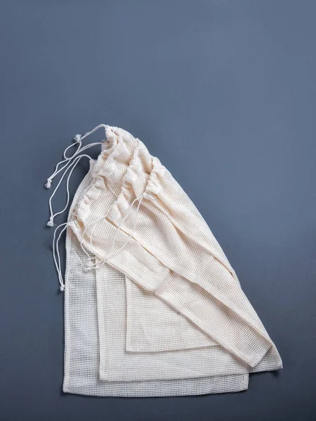 Białe torby strunowe wielokrotnego użytku do różnych produktów na szarym tle z przestrzenią do kopiowania. — Zdjęcie stockowe