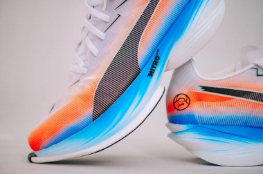 BERLİN, ALMANY, 29. Puma Fast-R Nitro Elit 3, geniş bir bakış açısıyla gösterildi, cesur beyaz-mavi-turuncu tasarımı ile yol hızı için yapılmış yeni nesil modern süper ayakkabıları vurguluyor..