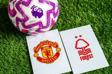 LONDON, UNITED KINGDOM, FEBRUARY 23, 2026: Manchester United - Nottingham Ormanı İngiltere Premier Ligi çatışması, kulüp armaları ve taze yeşil çimen arka planında futbol topu.