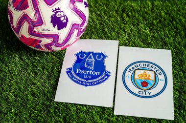 LONDON, UNITED KINGDOM, FEBRUARY 23, 2026: Everton - Manchester Premier Ligi çatışması, kulüp armaları ve taze yeşil çimen arka planda futbol topu.
