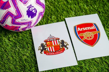 LONDON, UNITED KINGDOM, FEBRUARY 23, 2026: Sunderland-Arsenal İngiliz Premier Ligi çatışması, kulüp armaları ve taze yeşil çimen arka planında futbol topu.