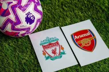 LONDON, UNITED KINGDOM, FEBRUARY 23, 2026: Liverpool-Arsenal İngiliz Premier Ligi çatışması, kulüp armaları ve taze yeşil çimen arka planında futbol topu.