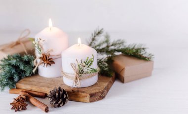 Noel mumları, hediye ve köknar dalları beyaz ahşap arka planda ışıklarla. Kopyalama alanı olan tebrik kartı