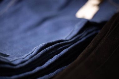 Dükkanda bir yığın mavi ve siyah kot pantolon. Alım, satım, alışveriş ve kot pantolon modası kavramı. Kotun deseni yakın plan..