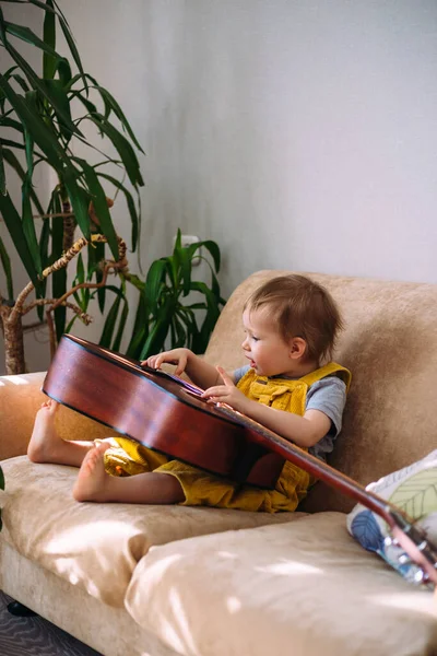Niño Lindo Juega Con Una Gran Guitarra Acústica Casa Sofá — Foto de Stock