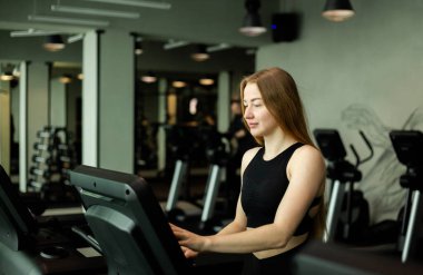 Spor salonunda koşu bandında koşan mutlu bir kadın..