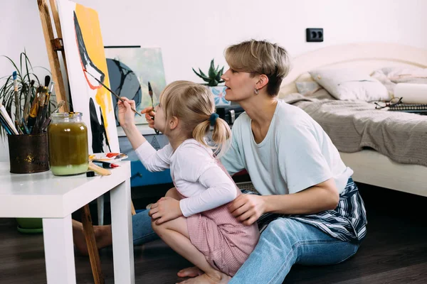 Güzel anne ressam ve çocuğu evde akrilik boyalarla resim yapıyorlar.. — Stok fotoğraf