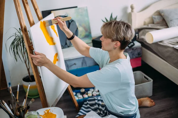 Jonge vrouw kunstenaar schildert thuis in een creatieve studio setting. — Stockfoto