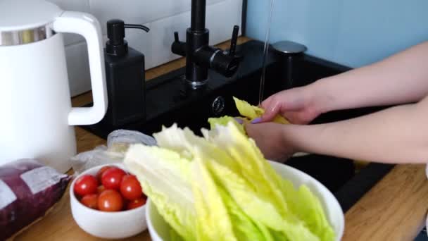 Kobiety myją ręce pod kranem w kuchni sałata romańska. — Wideo stockowe