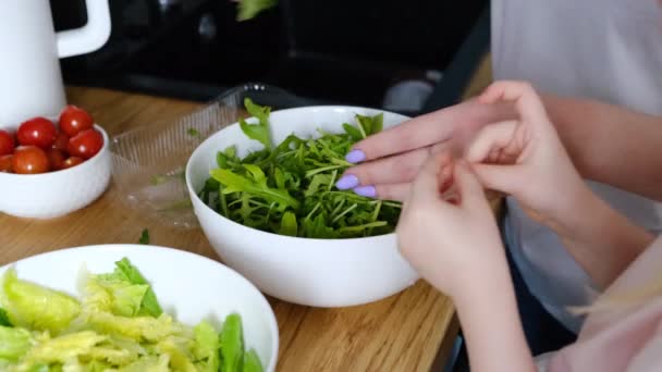 Dottern hjälper sin mamma i köket att laga hälsosam lunch och reda ut ruccola — Stockvideo