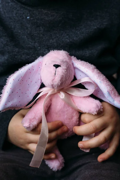 Дитячі руки тримають маленьку м'яку іграшку для кроликів. Соціальна реклама . — стокове фото